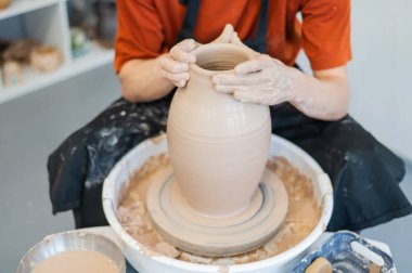 Çömlekçi elleriyle çömlekçi çarkında seramik vazo yaparken.