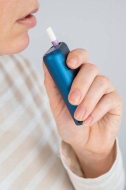 Elektronik sigara içen beyaz bir kadın. Tütün ısıtma sistemi