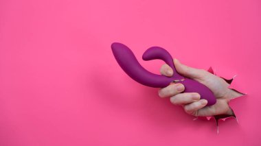 Pembe kağıttan yapılmış ahududulu seks oyuncağıyla takılan bir kadın eli.