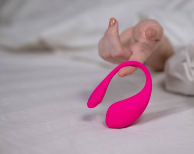 Yatakta uzanırken kavisli pembe vibratör tutan kadın.