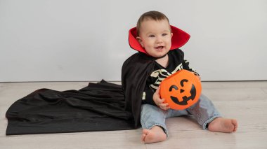 Beyaz arka planda şeker sepeti tutan Dracula Cadılar Bayramı kostümlü beyaz tatlı çocuk.