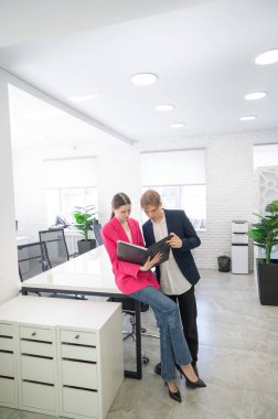 Meslektaşlar belgeli bir klasöre bakar ve iş konularını tartışırlar