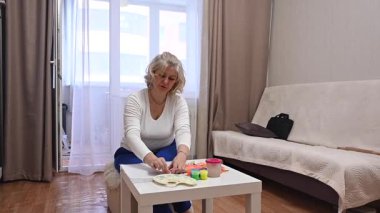 Evde kalemle çizen olgun bir kadın.