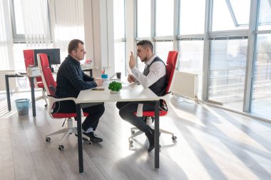 İki beyaz adam bir iş toplantısında iletişim kuruyor.