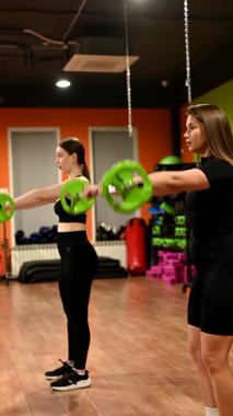 İki beyaz kadın halter egzersizi yapıyor.