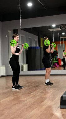 İki beyaz kadın halter egzersizi yapıyor.