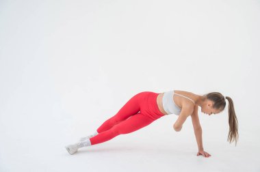 Genç bir kadın beyaz arka planda yan tahtalar ve kıvrımlar yapıyor.