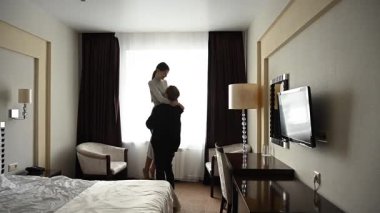 Beyaz bir çift pencerenin önünde dikilirken sarılıyor.