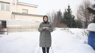 Beyaz yaşlı kadın kışın kuş yemliğine yemek koyuyor.