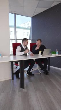 İki beyaz adam bir masada oturup iş tartışıyorlar.