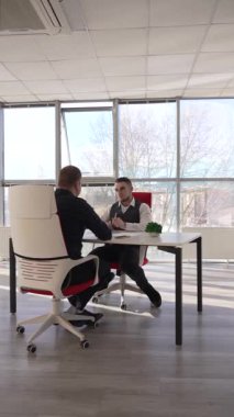 İki beyaz adam bir iş toplantısında iletişim kuruyor.