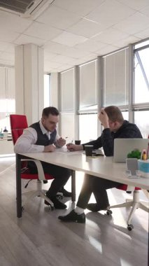 İki beyaz adam bir masada oturup iş tartışıyorlar.