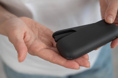 Bir kadın, tütün ısıtma sistemini şarj aletinden çıkarır. Elektronik sigara.