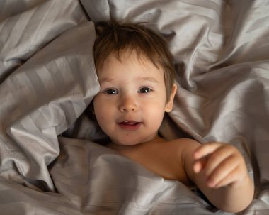 Beyaz tenli şirin bir çocuğun yatakta yatışının üst görüntüsü.