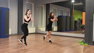 Spor salonunda hamleler yapan iki beyaz kadın.