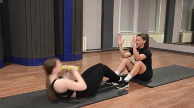 Karın egzersizi yapan iki beyaz kadın.