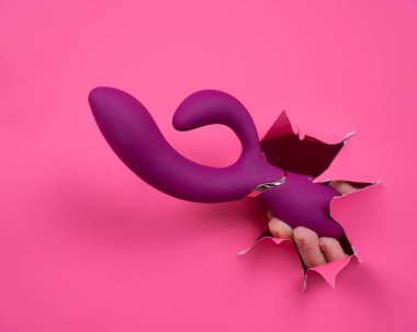 Pembe kağıttan yapılmış ahududulu seks oyuncağıyla takılan bir kadın eli.
