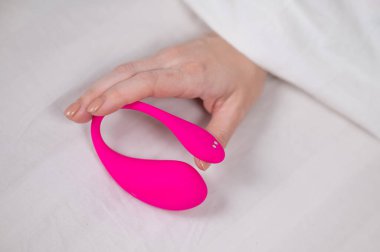 Yatakta uzanırken kavisli pembe vibratör tutan kadın.