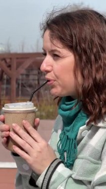 Beyaz kadın dışarıda kahve içiyor.