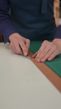 Deri işçisi atölyede deri kesip ölçüyor.