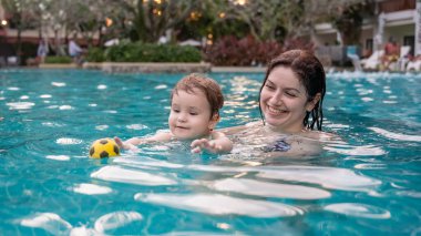 Beyaz kadın tatilde havuzda yüzerken oğlunu kucağına aldı