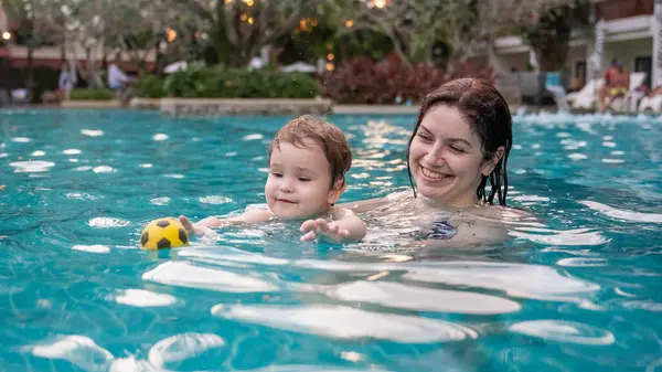 Beyaz kadın tatilde havuzda yüzerken oğlunu kucağına aldı