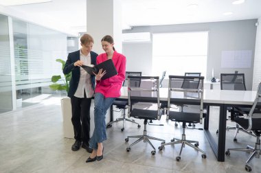 Meslektaşlar belgeli bir klasöre bakar ve iş konularını tartışırlar