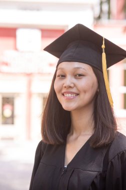 Mezuniyet elbisesi içindeki mutlu Asyalı kadın.