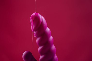 Lube pouring on pink dildo on pink background