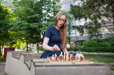 Beyaz kadın dışarıda satranç oynuyor.