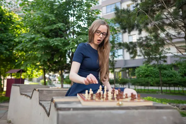 Beyaz kadın dışarıda satranç oynuyor.