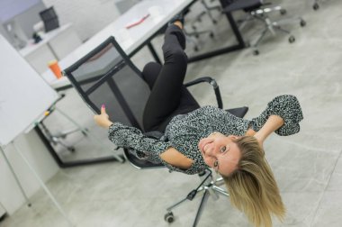 Beyaz kadın eğleniyor ve ofis sandalyesinde uzanıyor.