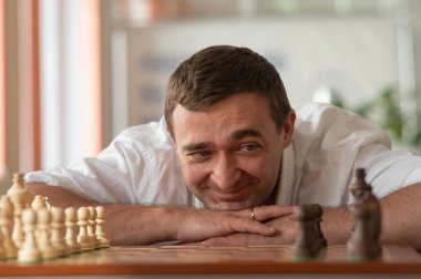 Orta yaşlı beyaz adam satranç oynuyor.