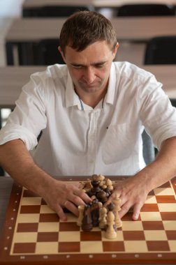 Orta yaşlı beyaz adam satranç oynuyor.