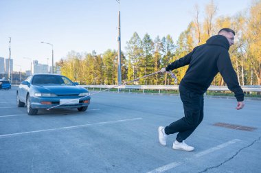 Beyaz bir adam halatla araba çekiyor.