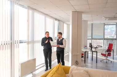 İki beyaz adam dizüstü bilgisayara bakıyor ve iş tartışıyorlar.