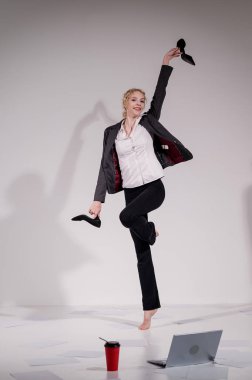 Beyaz arka planda iş elbisesiyle dans eden çıplak ayaklı balerin.