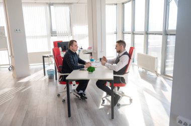 İki beyaz adam bir iş toplantısında iletişim kuruyor.