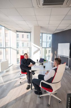 Bir ofiste pazarlık yapan iki beyaz adam.