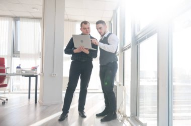 İki beyaz adam dizüstü bilgisayara bakıyor ve iş tartışıyorlar.