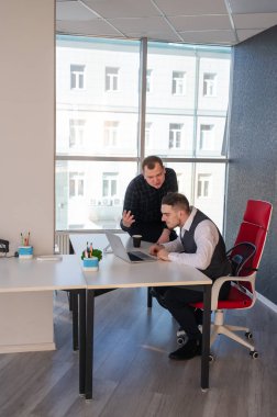 Beyaz adam çalışma masasında durmuş iş hakkında konuşuyor.