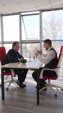 İki beyaz adam bir iş toplantısında iletişim kuruyor.