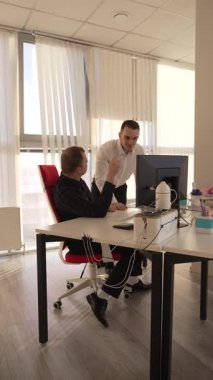 Beyaz adam çalışma masasında durmuş iş hakkında konuşuyor.