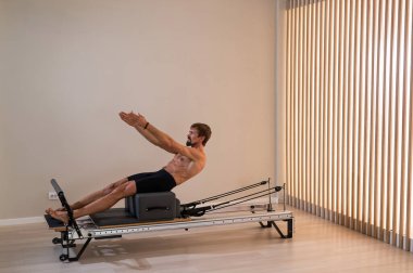 Reformcu üzerinde pilates yapan bir adam.