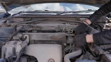 Beyaz adam bujileri değiştiriyor ve yüksek voltajlı kabloları söküyor.