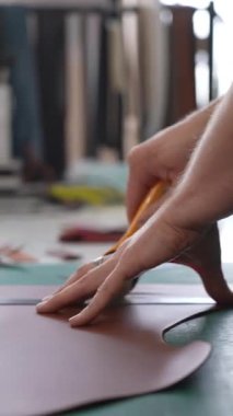 Deri işçisi atölyede deri kesip ölçüyor.