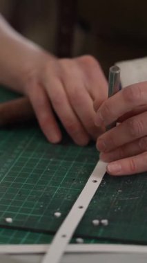 Bir kadın atölyede deri kemerde delikler açıyor.