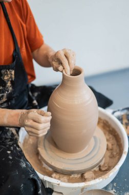 Çömlekçi elleriyle çömlekçi çarkında seramik vazo yaparken. Dikey fotoğraf