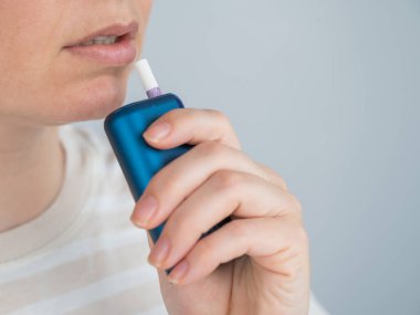 Elektronik sigara içen beyaz bir kadın. Tütün ısıtma sistemi