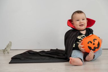 Beyaz arka planda şeker sepeti tutan Dracula Cadılar Bayramı kostümlü beyaz tatlı çocuk.